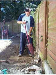Man with spade digs to build patio